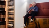 Foto på en person som sitter och läser i en soffa.