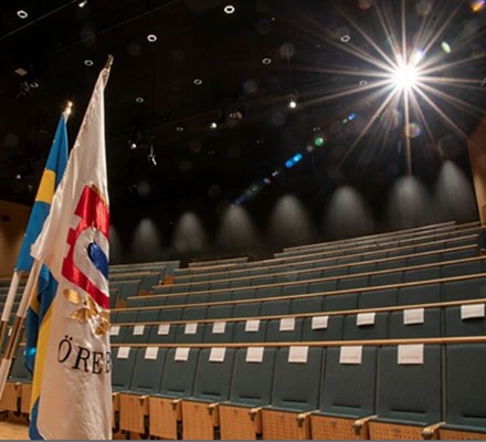 Bild på Tidefeltsalen från scenen - överblick över stolsrader. Flaggor på scenen.