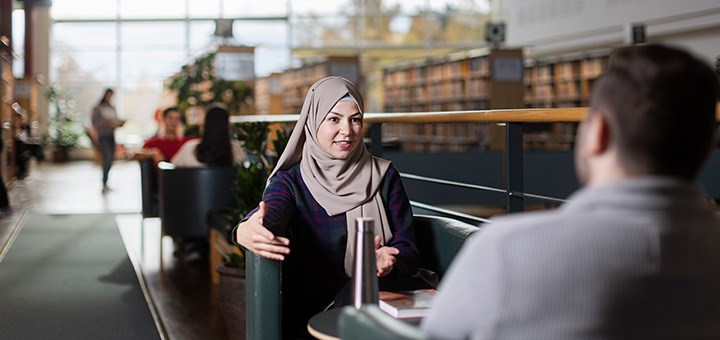 Två studenter sitter och pratar med varandra.