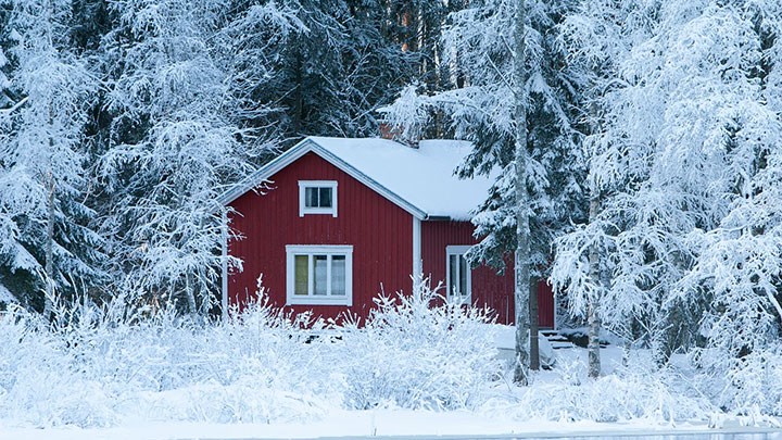 A red cottage in a winter landscape.