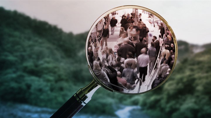 A forest landscape in the background and, in the foreground, a magnifying glass held over a busy urban environment, symbolising the link between environmental impacts and society.