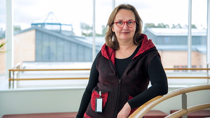 Izabela Dahl står vid en trappa. Det är ett fönster bakom henne.