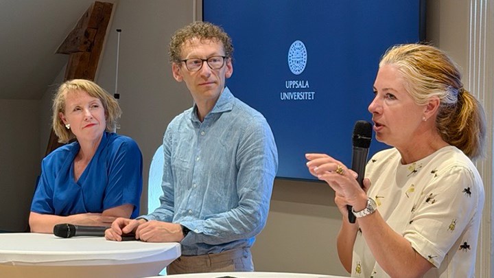 Två kvinnor och en man i samtal vid ståbord. En av kvinnorna har en mikrofon i handen. 
