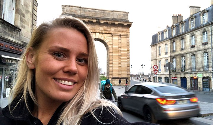 Elin i en selfie framför en gammal portal i stadsmiljö.