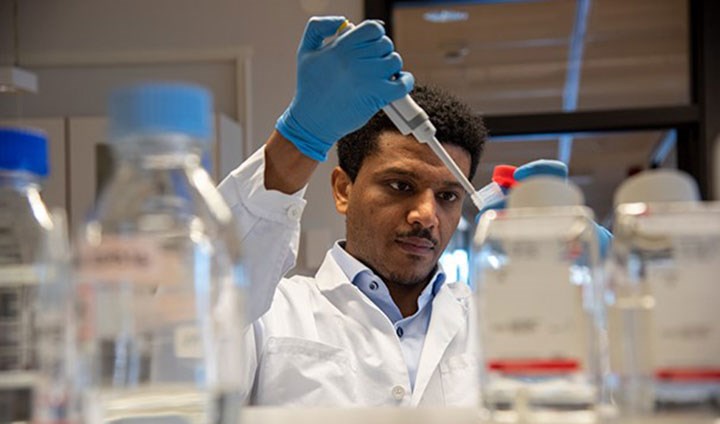 En forskare tar prover i ett labb med flaskor.