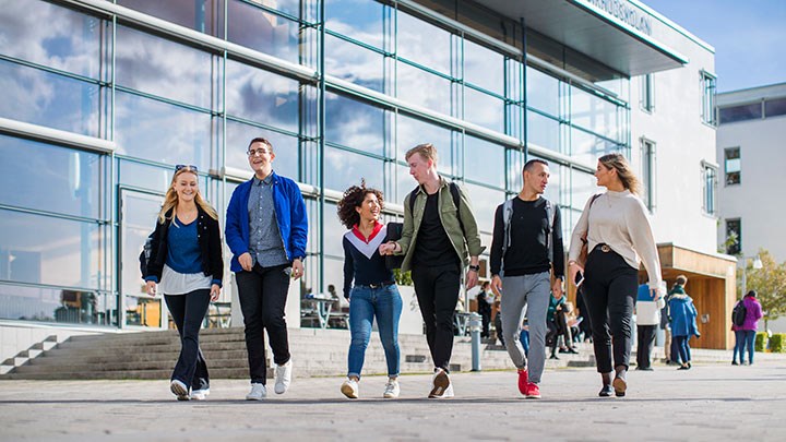 Studenter promenerar i grupp utanför byggnad.