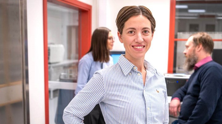 En person med handen på höften med två personer pratande bakom.