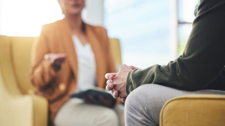 Två personer som sitter ner i varsin fåtölj och samtalar med varandra