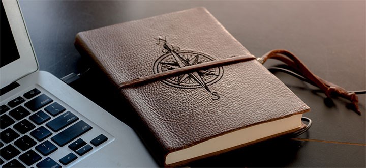 En bok med en kompass ligger på en öppen laptop