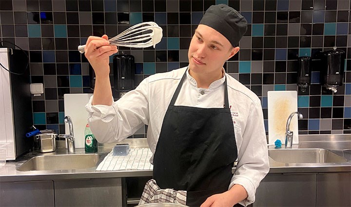 Erik Jönsson i köket med en visp i handen.