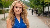 Maria Camacho Doyle, fotograferad på universitetsområdet med en väg och några suddiga personer i bakgrunden.