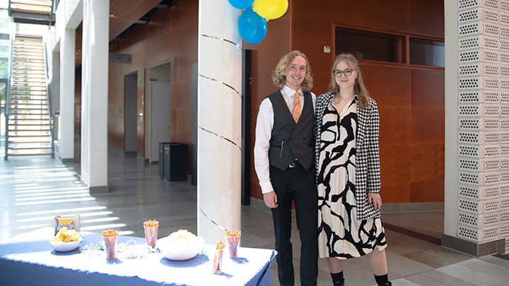 Jonas Törnqvist och Julia Norén står vi ett bord med salta pinnar och blå duk. Ovanför dem hänger ballonger på en pelare.