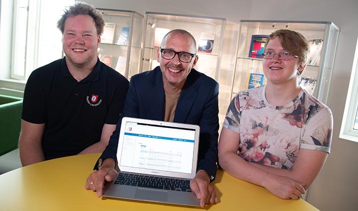 Magnus Hansson från Handelshögskolan sitter bakom en laptop tillsammans med informatikstudenterna David Wirén och Gustav Haglund.
