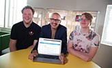 Magnus Hansson från Handelshögskolan sitter bakom en laptop tillsammans med informatikstudenterna David Wirén och Gustav Haglund.