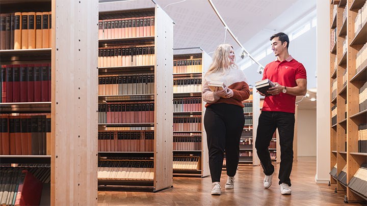 Två studenter på Örebro universitet med biblioteker i händerna.