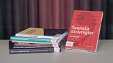 Foto på fem språk- och skrivhandböcker som står och ligger på ett bord.