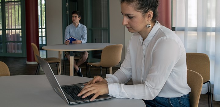 Photo of a student sitting at a table with a computer