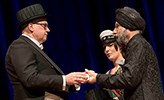 Three people, one receiving a diploma