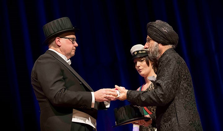 Three people, one receiving a diploma