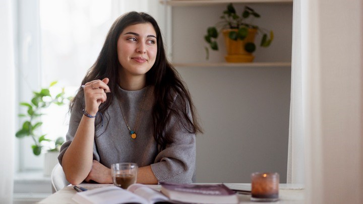 En student sitter vid bordet och tänker.
