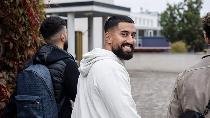 Tre manliga studenter går ute på campus.