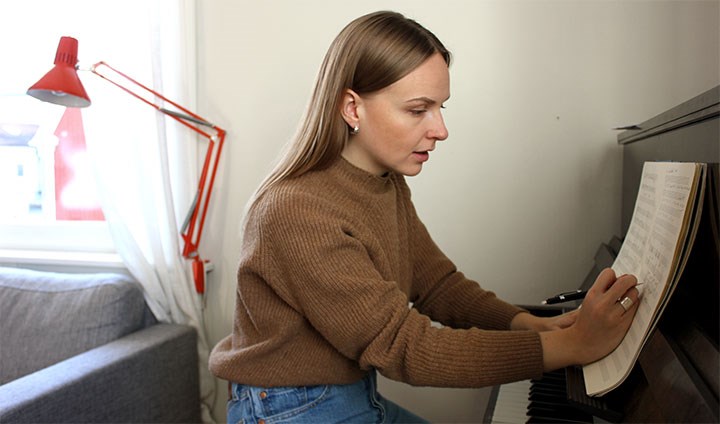 Linnea Landström skriver musik sittande vid sitt piano.