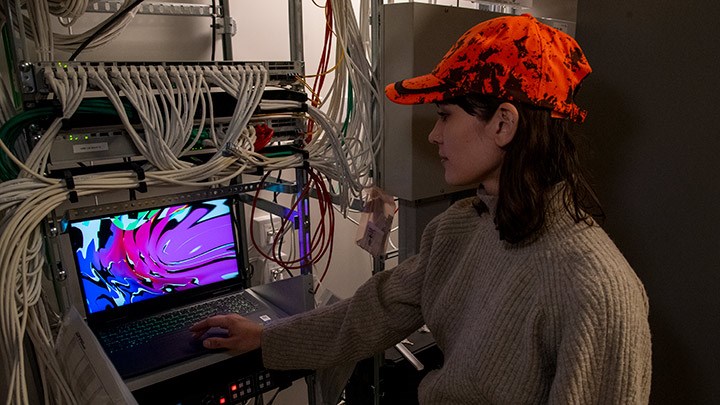 Konstnären Izabel Lind vid en dator i ett rack. Datorn visar en animation.