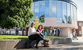 Studenter i samspråk utanför universitetsbiblioteket.