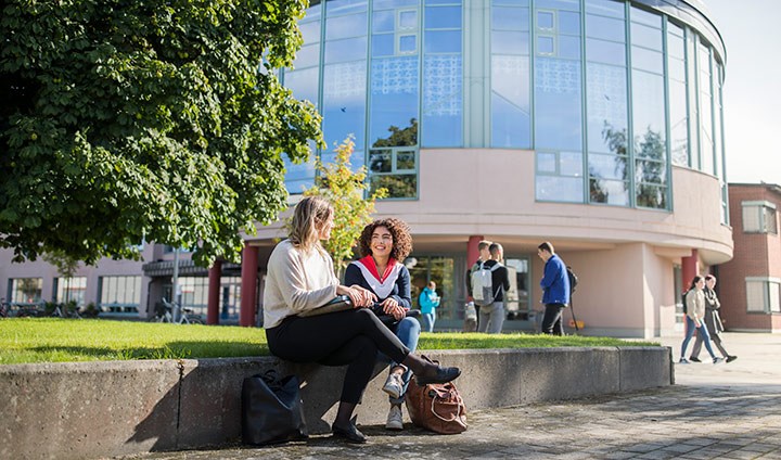 Studenter i samspråk utanför universitetsbiblioteket.