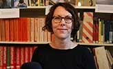 Jenny Hedström sitting in front of shelves of books.