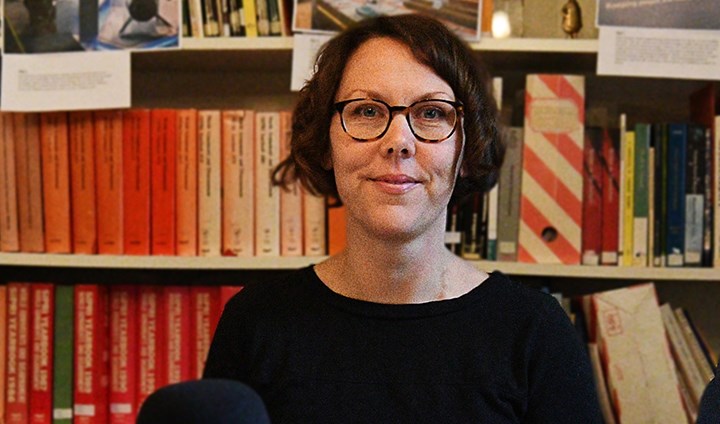 Jenny Hedström sitting in front of shelves of books.