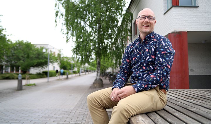 A smiling Niklas Eriksen sitting outside on a bench.