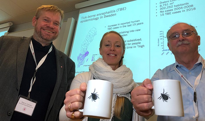 Anna Överby och Gerhard Dobler håller fram varsin kaffemugg med en fästing på. Bredvid dem står Magnus Johansson.