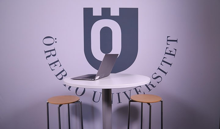 Ett bord och två stolar och Örebro universitets logotyp bakom.