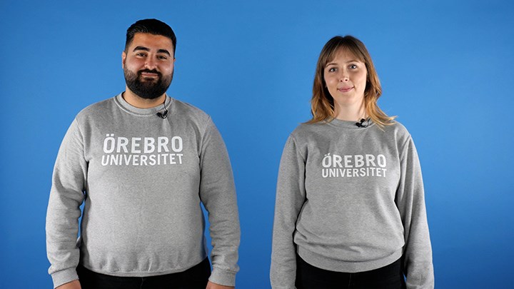 Två studenter står vid en blå bakgrund.