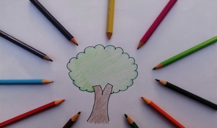 Tecknad bild med träd och färgpennor i cirkel med spetsen in mot trädet i mitten