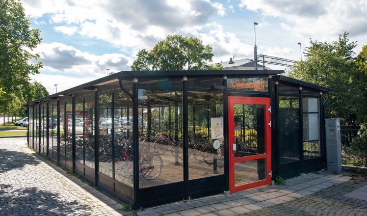 Exteriörbild av Örebro kommuns cykelgarage, en låg byggnad med stora glasfönster runt om.
