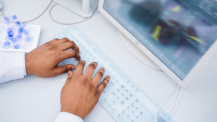 Foto på två händer som använder ett tangentbord.