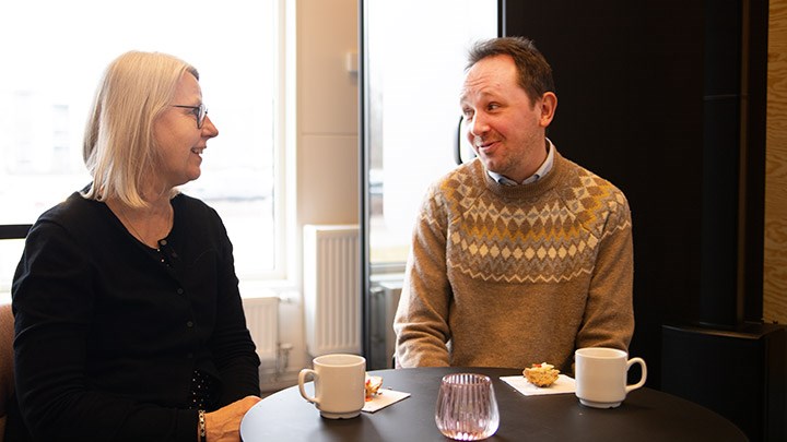 Lis Sjöberg och Joakim Norberg pratar. Det står kaffekoppar på bordet.