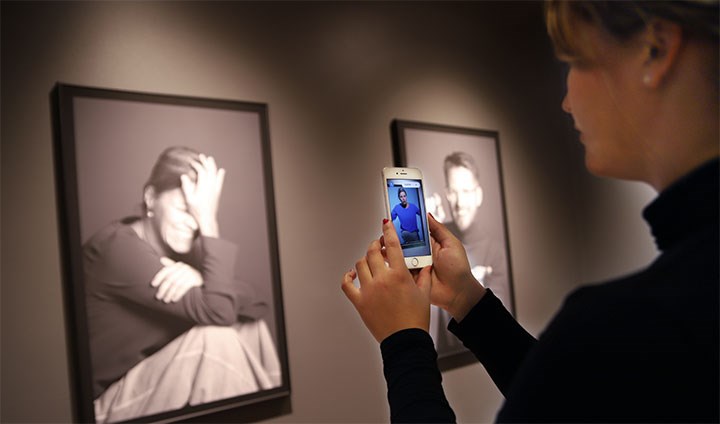 En student tittar på ett porträttfotografi som aktiverar en film i hennes mobiltelefon.