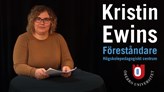 Bild på Kristin Ewins ståendes vid ett runt bord med mörkgrön duk hållandes i ett häfte med pappersark.