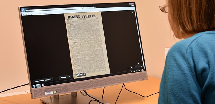 Foto på person som sitter vid en dator med artikel från Svesnska dagstidningar på skärmen.