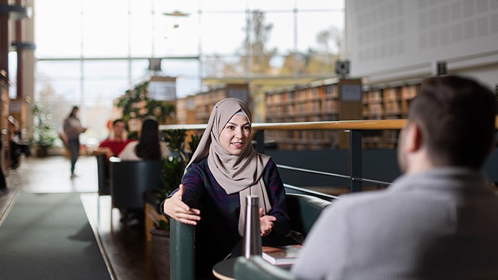 Två studenter sitter i biblioteket.