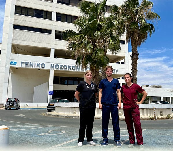 Tre studenter framför ett sjukhus