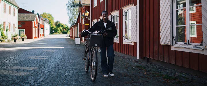 En student går med cykeln i ett soligt Grythyttan.