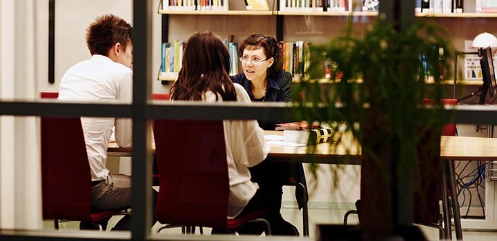 Två studenter sitter vid ett bord med handledare