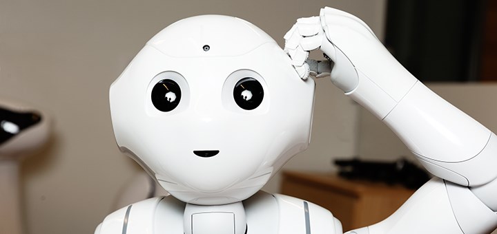 En robot tittar in i kameran och kliar sig i huvudet.
