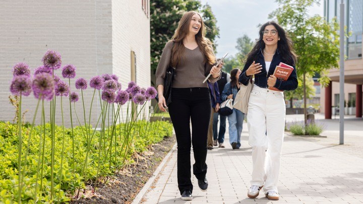 Två studenter går på ett soligt campus.