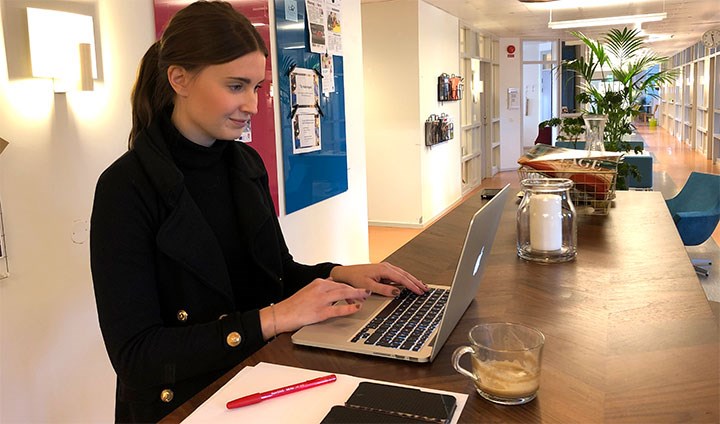 Kajsa-Stina Pettersson skriver på en laptop vid ett bord.