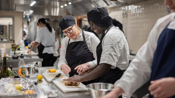 En kock visar och instruerar matvaror för några kockstudenter.
